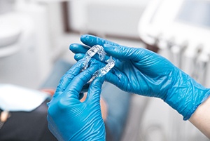 Dentist holding clear aligners with gloves