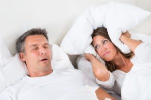 Woman closing her ears next to her husband sleeping