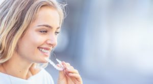 young attractive woman smiling inserting Invisalign in Virginia Beach