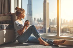 Woman inside during quarantine looks outside through a window