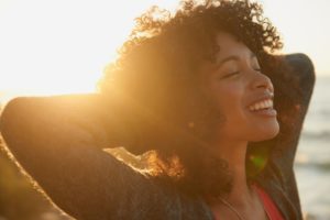 woman smiling in the sunset after seeing cosmetic dentist in Virginia Beach 