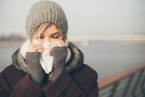a woman with a cold blowing her nose