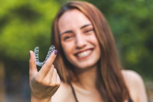 a woman smiling with her Invisalign treatment